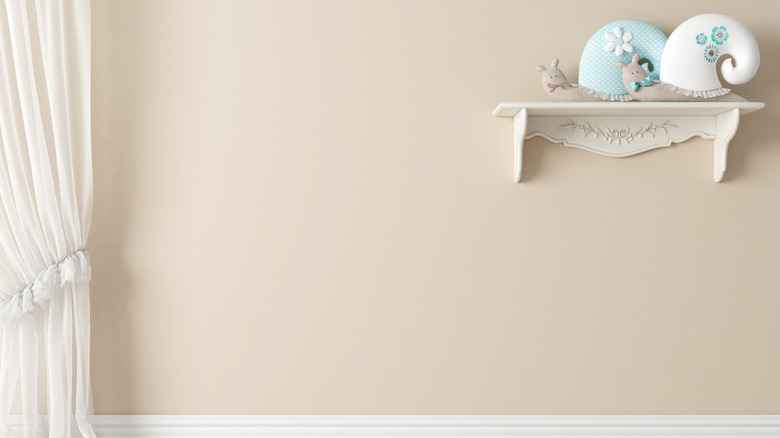 Wall painted warm off-white with floating shelf holding snail-shaped plush decorations.