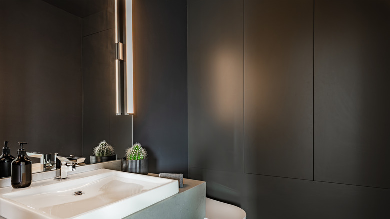 Deep gray paint on the walls of a bathroom, next to sink and vanity.
