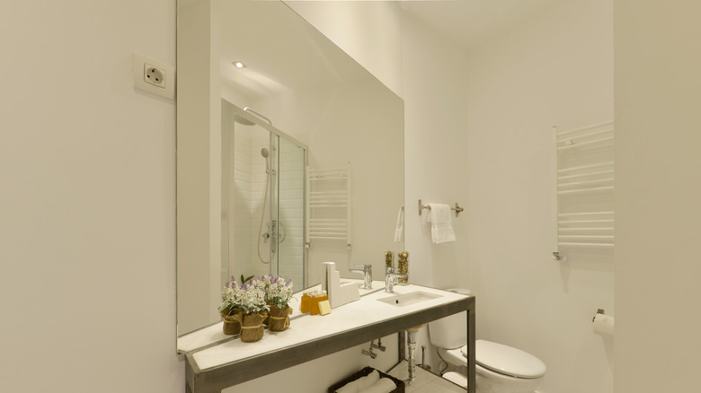 A builder-grade frameless mirror hangs in an oddly-shaped bathroom