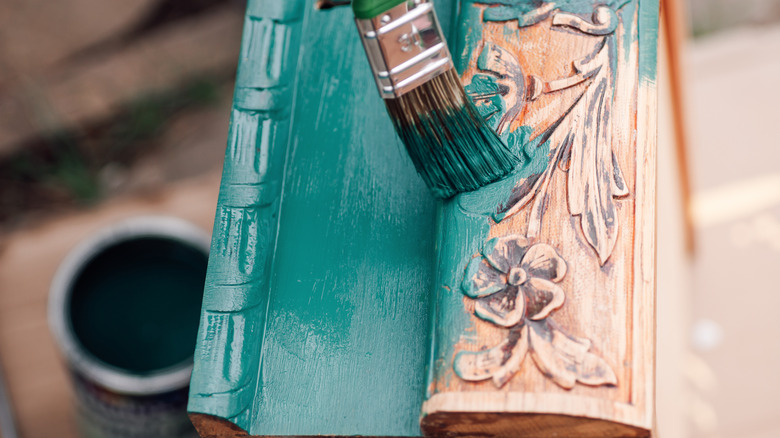 Teal paint being brushed onto antique wood