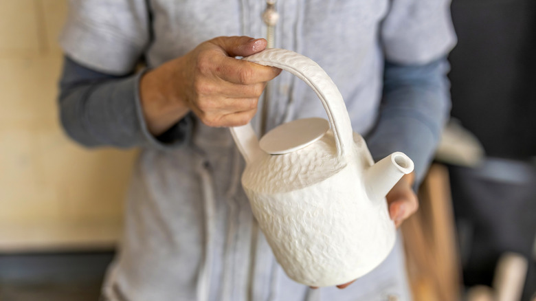 woman holding white textured teapot