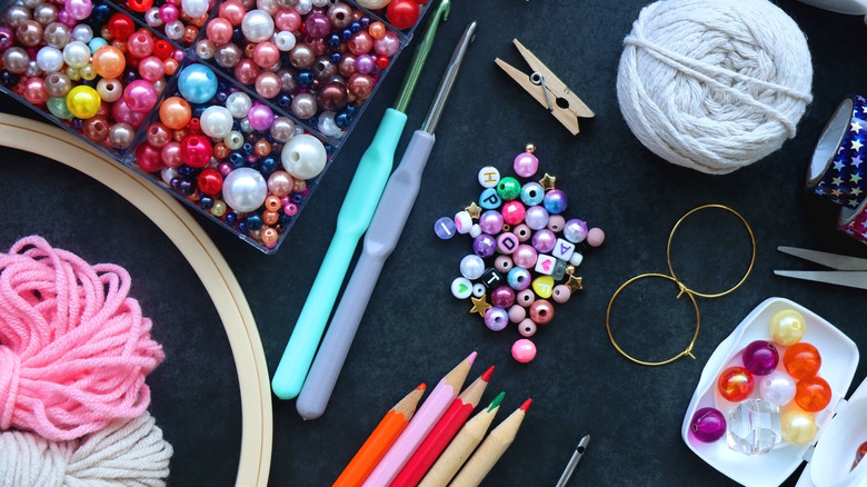 Beads, string, colored pencils, and other craft supplies spread out on a surface