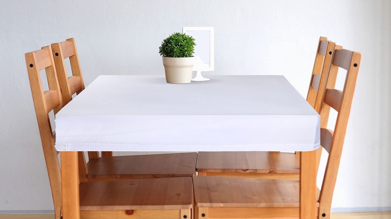 A table covered by a fitted white tablecloth.