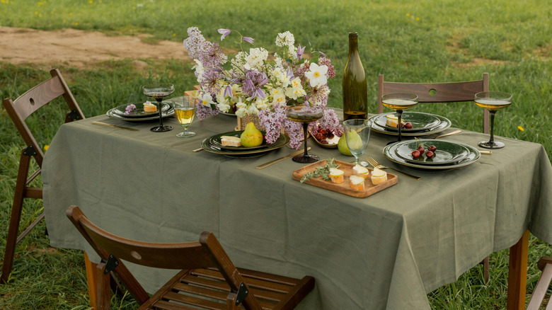 An outdoor table covered by a green tablecloth and set for a meal.