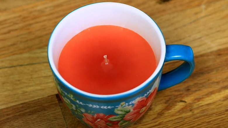 A DIY candle made inside a ceramic cup with a floral pattern.