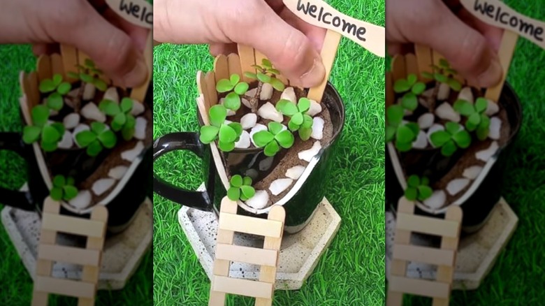 Person creating a fairy garden with a broken mug