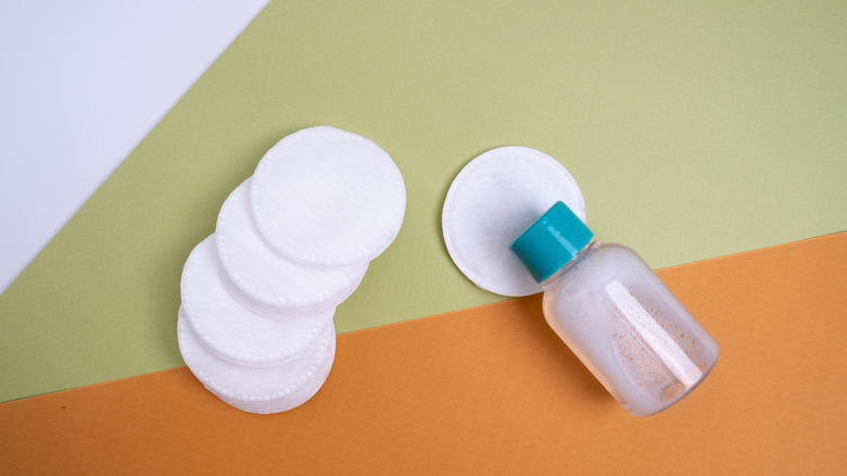 A pile of cotton pads and a bottle.
