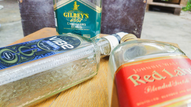 One empty glass bottle stands next to two on their sides on a table