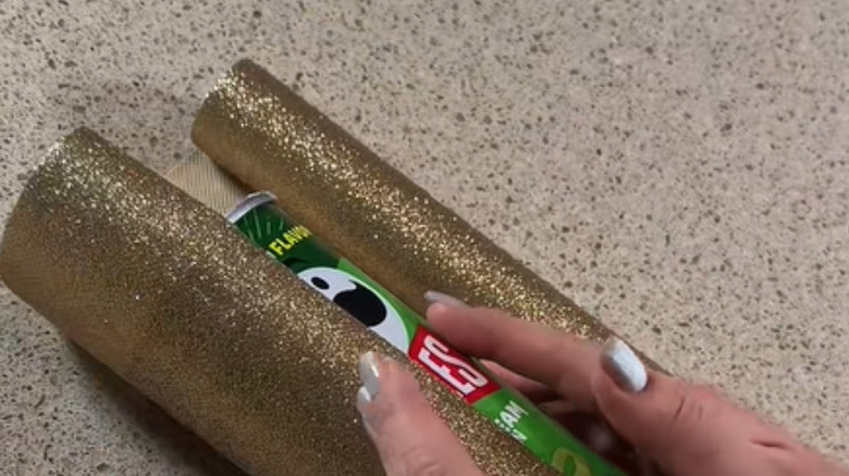 Person wrapping pringles can with glittery paper
