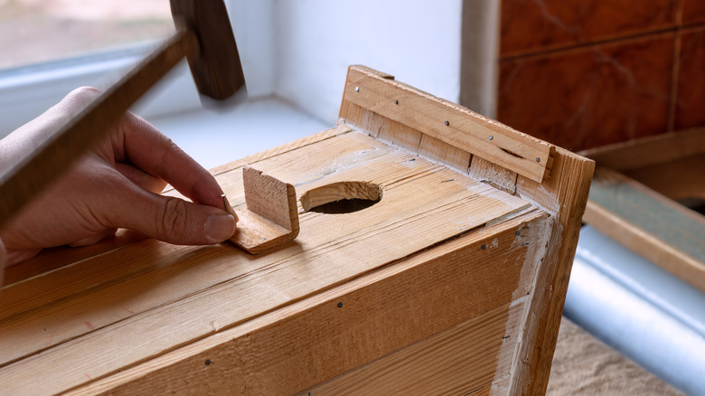 A person building a birdhouse from scrap wood