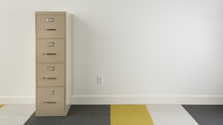 File cabinet against wall on striped carpet