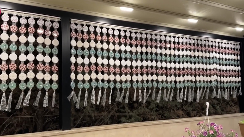 A privacy screen made of upcycled jar lids and lace
