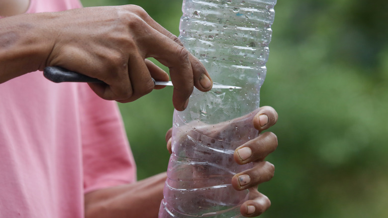 woman cutting plastic bottle