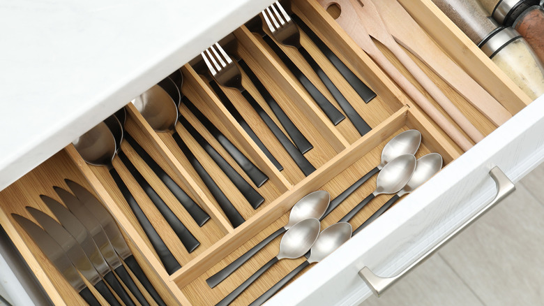 Utensils in a wooden silverware organizer inside a drawer