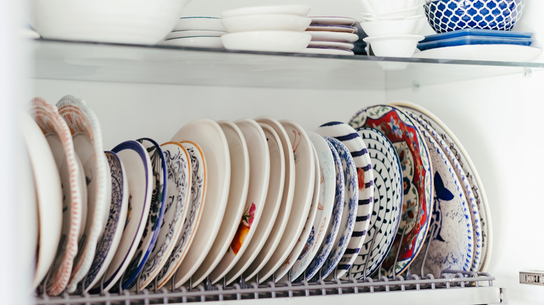 thrifted vintage plates lined up in a cupboard