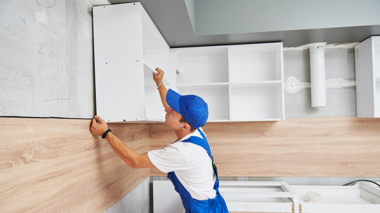 man working with upper kitchen cabinets