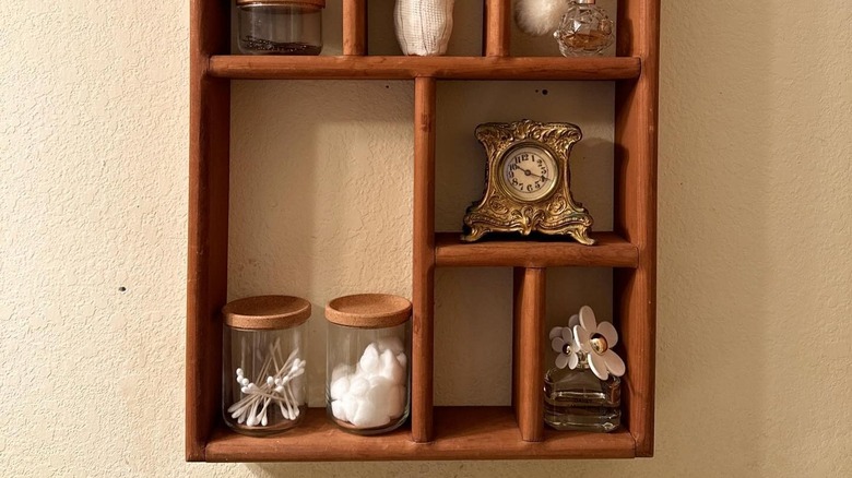 Wooden shelf holding bathroom supplies and decor