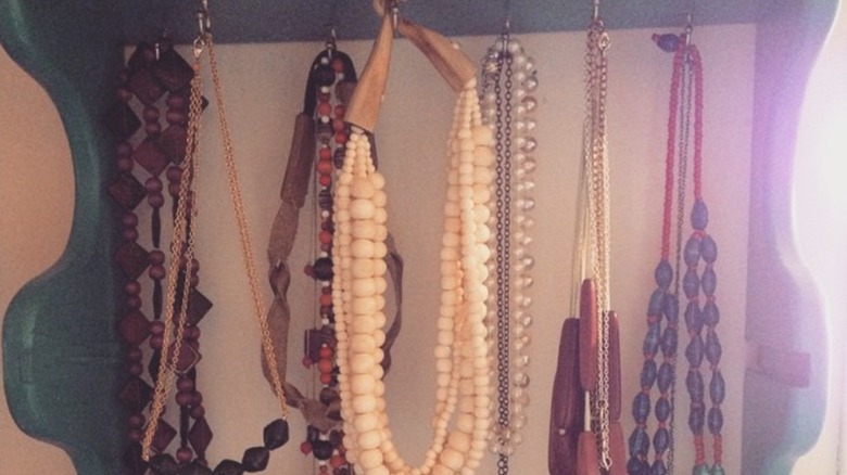 Jewelry hanging from hooks on wood shelf unit
