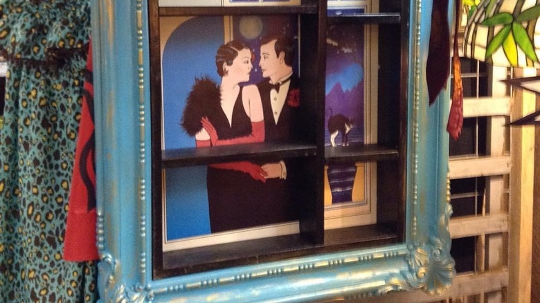 Poster print behind narrow shelf unit