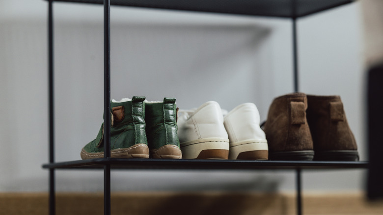 Close-up of three pairs of shoes on a black metal shoe rack