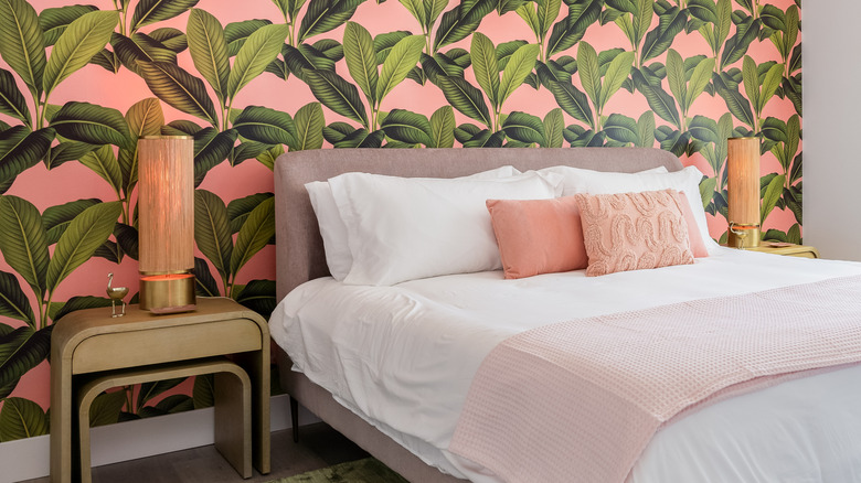 Bedroom with tropical patterned pink accent wall behind bed