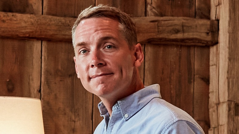 Clint Harp posing in front of wooden walls