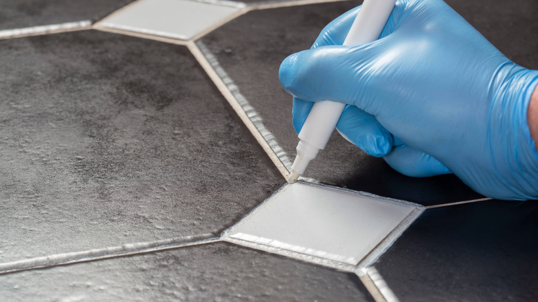A person using a grout pen to refresh tile flooring