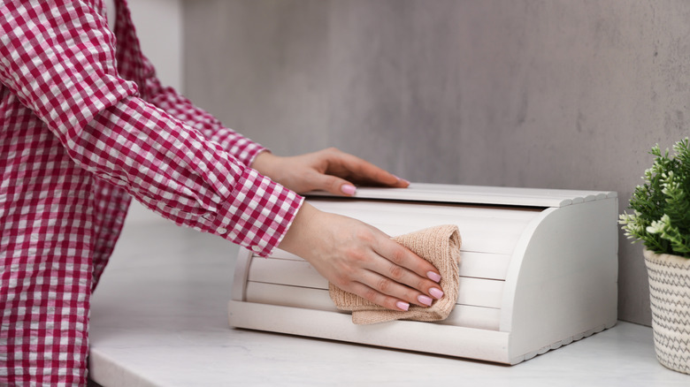 Hands wiping down a bread box