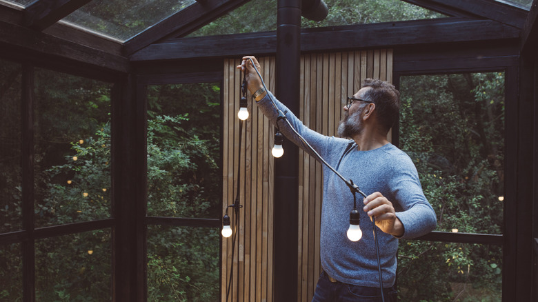A person removes the string lights from his covered patio.