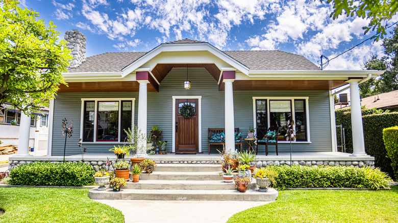 a bungalow house with a front porch decorated with potted plants