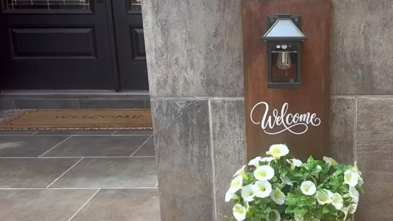 a DIY planter box with flowers and a solar light on a front porch