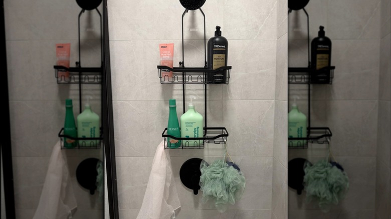 A black Joqixon shower caddy hanging over a black shower with several bath products on it