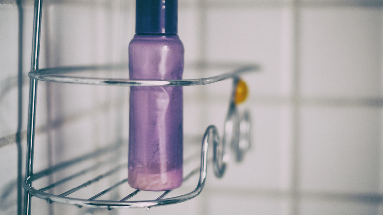 Closeup of a silver metal shower caddy with a purple bottle sitting on it