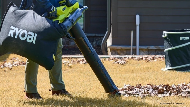 Person vacuuming loose leaves from a lawn with the Ryobi leaf blower and vacuum