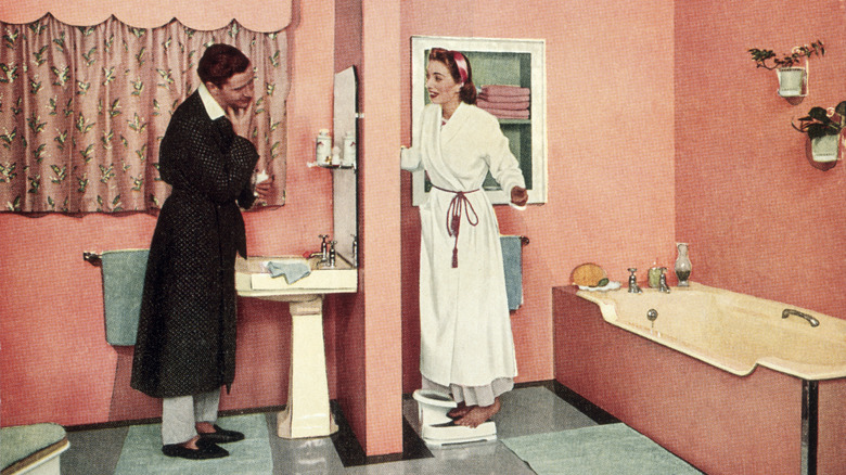 A couple in bathrobes in a 1950s bathroom.