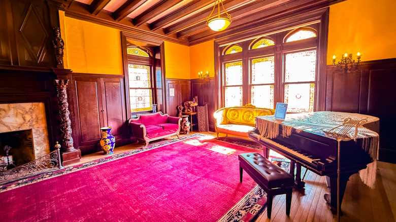 a room with piano, sofas, and elaborate fireplace