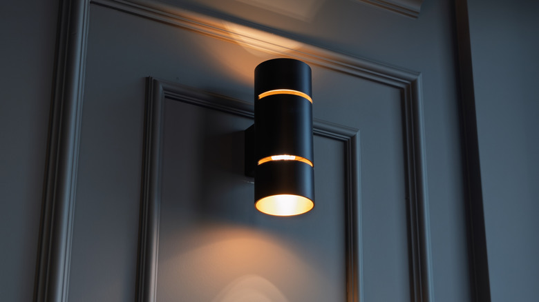 Black sconce with rings on a dark door