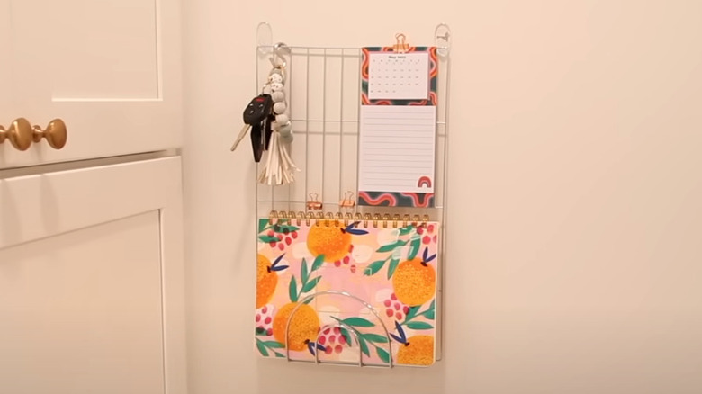 woman putting keys on wire cooling rack mounted to wall