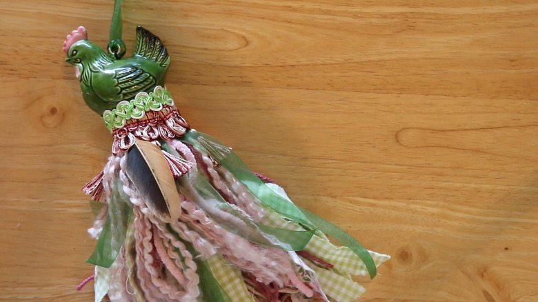 A green rooster salt shaker tassel laying on a wooden table