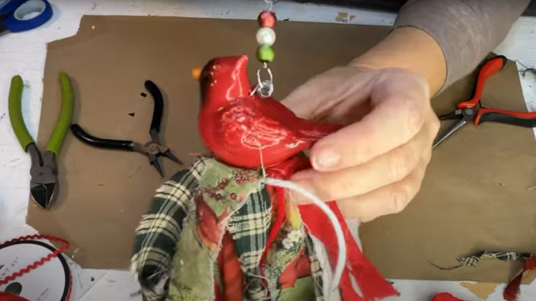 A hand holding a Christmas cardinal tassel
