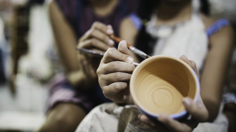 People painting a clay bowl