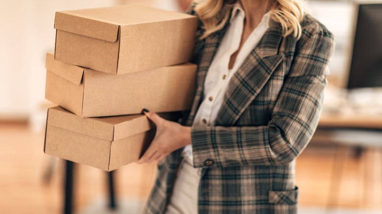 Person carrying stack of empty shoeboxes