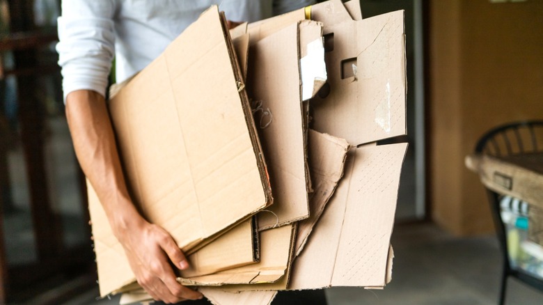 man carrying stack of old broken down cardboard boxes