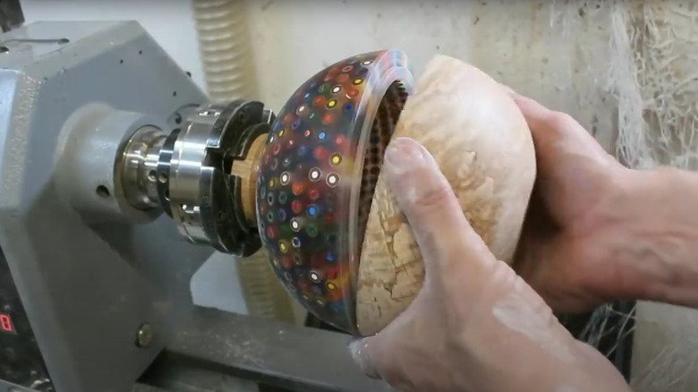 Hands adjusting DIY lamp parts on a woodturning lathe
