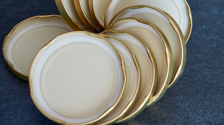 A collection of 10 canning jar lids in a pile on a blue surface
