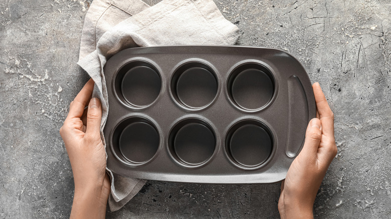 Person holds a metal muffin tin