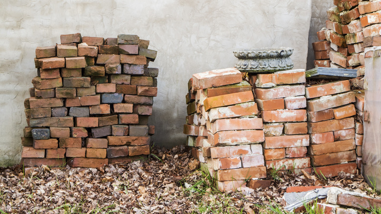 Stacks of old bricks against an outdoor plastered wall.