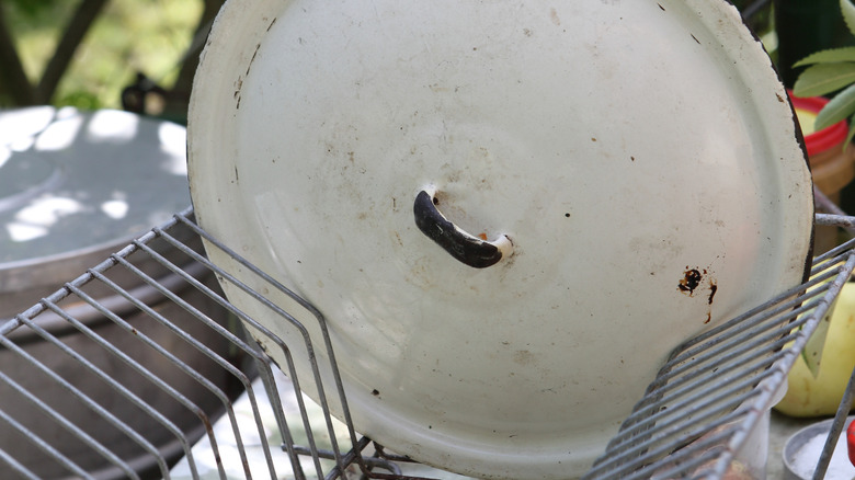A person lifts the lid off of a pot on the stove.