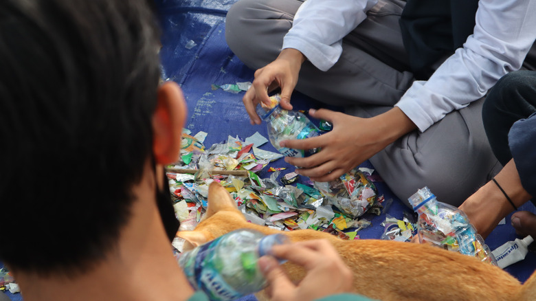 A group of people work together to make ecobricks from trash.