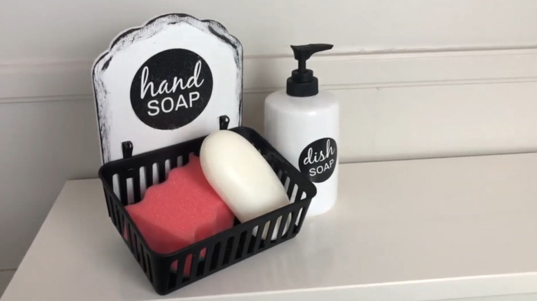 A sponge and bar soap sitting in a small storage tray with a sign behind it.
